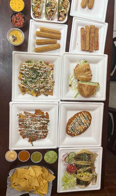 A table of tacos, nachos, tortas, flautas and churros
